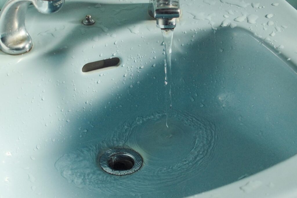 Close-up of water flowing from a faucet into a bathroom sink.